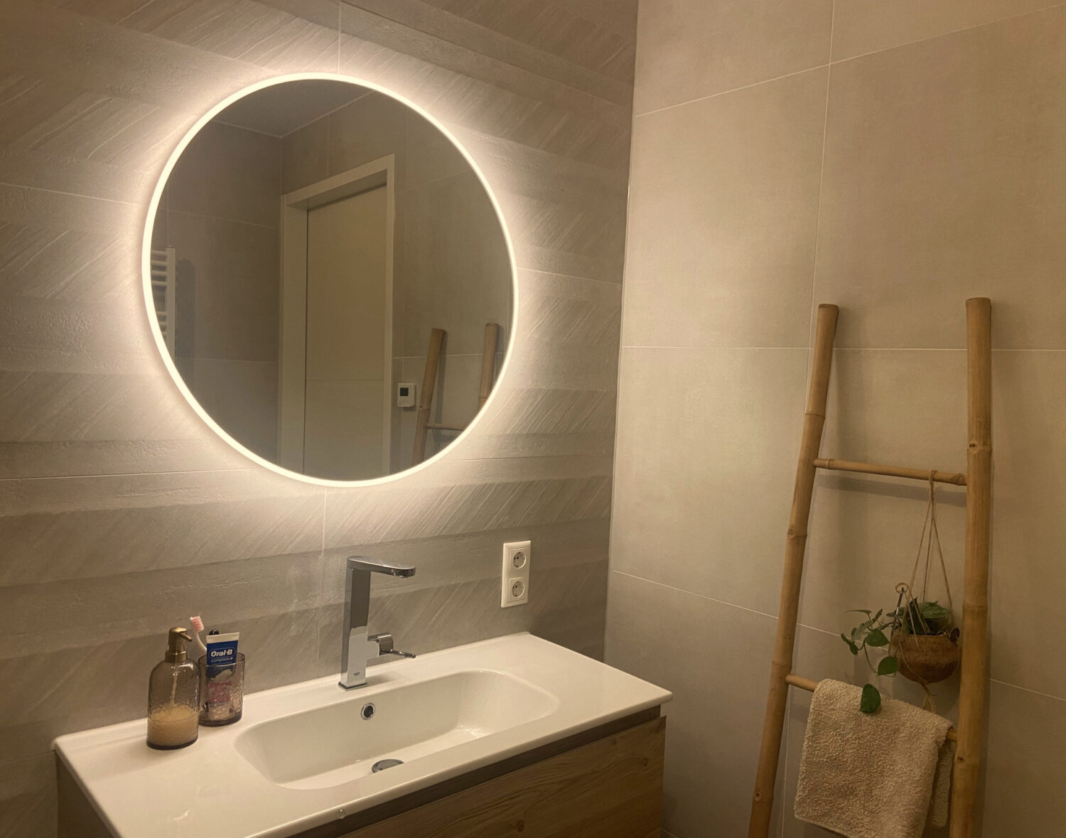 Ronde badkamer spiegel op een crème tegel met relief