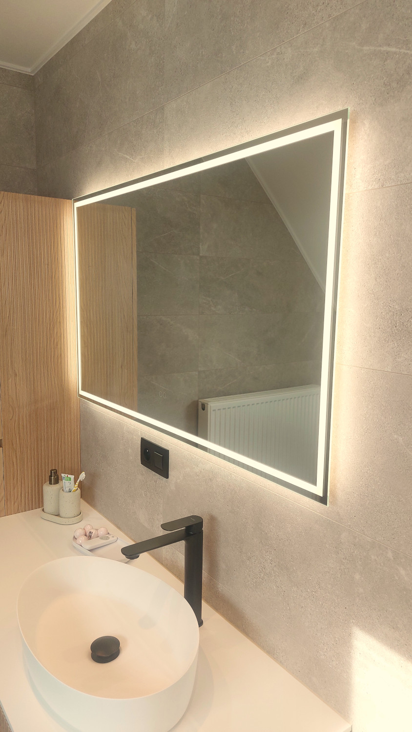 Moderne badkamer spiegel met rondom verlichting op een grijze tegelwand