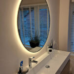 Zwarte ronde badkamerspiegel op gestuukte wand