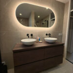 Grote ovale badkamer spiegel op taupe tegel