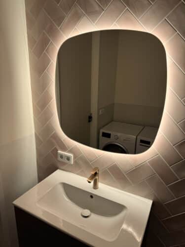 Deens ovale badkamer spiegel op roze tegelwand