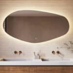 Deze stijlvolle badkamer spiegel met organische vorm is van alle gemakken voorzien, zoals: ambi verlichting, spiegelverwarming, dimfunctie en een instelbare lichtkleur